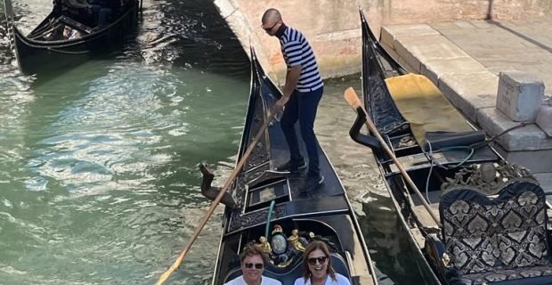 Happy couple of clients having fun on gondola in Venice, Italy