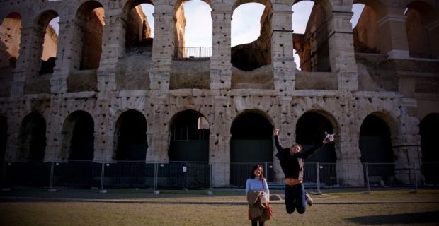 Happy couple of clients having fun in front of Colosseum in Rome, Italy