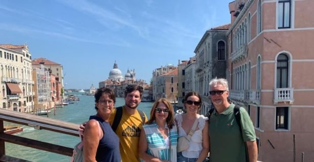 Happy family clients enjoy the beautiful view of the Grand Canal and Santa Maria della Salute in Venice, Italy from the Ponte dell'Accademia