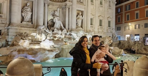 Trevi Fountain at night with a young couple with their child standing together in Rome, Italy